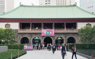 Visitors exiting a traditional Japanese building in Tokyo with Art Week Tokyo banners. Art travel guide.