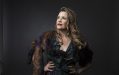 A profile photo of cabaret artist Ali McGregor, wearing a dark green dress with fur shoulder accents and flowy waves in her hair.