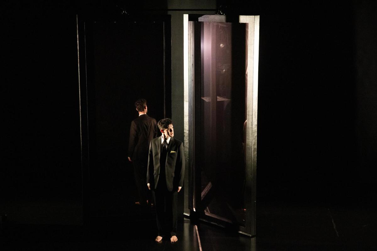 A young Aboriginal man in a black suit standing next to a large silver steel door frame.