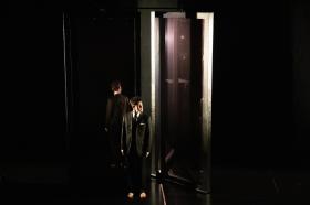 A young Aboriginal man in a black suit standing next to a large silver steel door frame.