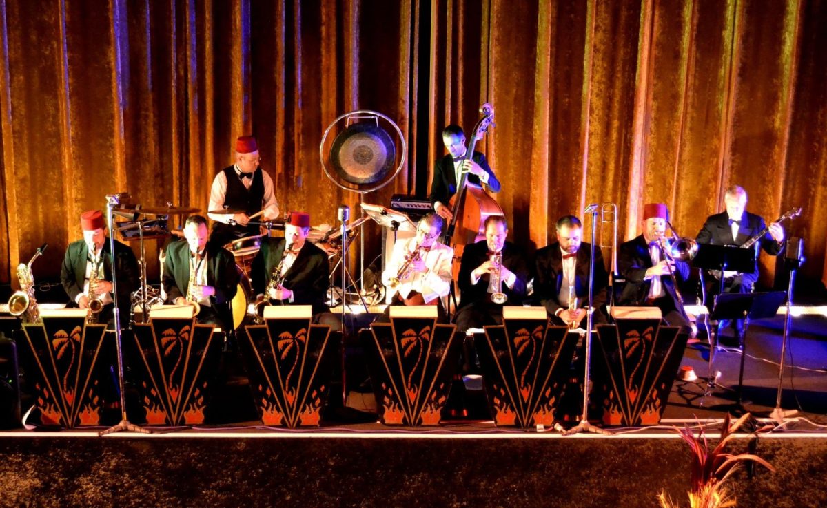 A band scene on stage. Several members are wearing red fez hats.
