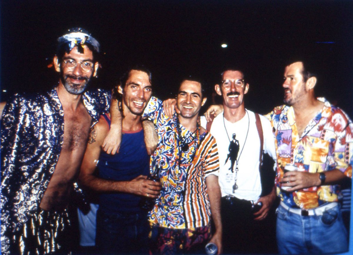 David McDiarmid: A photo of five young men aged in their thirties wearing colourful outfits against a dark backdrop.
