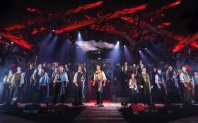 A large cast on stage in period costume.