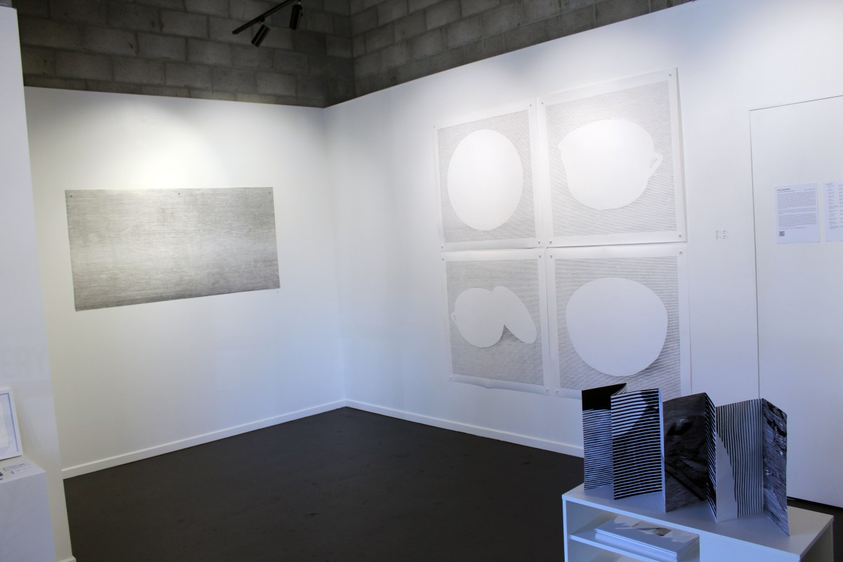 Grey and white lino prints against a white wall.