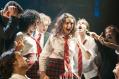 A group of young adults dressed in school uniform of white, red and black. They seem to be taunting a girl in the centre.