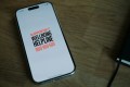A photograph of a smartphone showing the Support Act Wellbeing Helpline number: 1800 959 500.