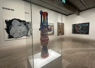 View of gallery exhibition with large ceramic sculpture in glass case. Wynne Prize.