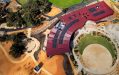 An aerial view of a red, dark red building surrounded by native trees, grasslands and an amphitheatre.