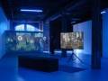 A gallery space with two video screens showing street scenes.