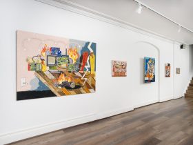 Bright, colour paintings on a white wall. The photo is taken on on the diagonal.