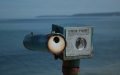 A metal object that looks like a view finder positioned by the water.