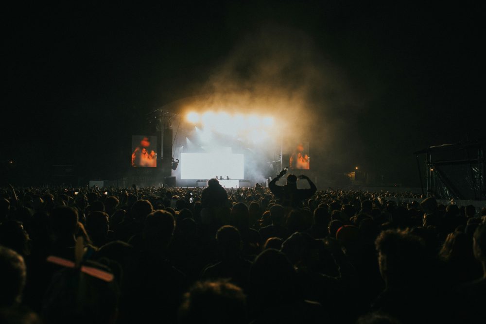 Crowd of music goers in front of a stage in a dark venue.