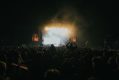 Crowd of music goers in front of a stage in a dark venue.