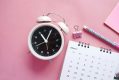 An old-fashioned alarm clock, a calendar, a pink paperclip and a pack of post-it notes photographed from above against a pink tabletop. ArtsHub's On the move column is a weekly round-up of Australian arts sector appointments and resignations.