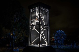 A person in a white spacesuit in a see-through two level structure.