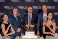 Guests assemble at the cake-cutting ceremony for Canberra Theatre Centre's 60th anniversary. Three fair-skinned men in suits, flanked by two ballerinas from The Australian Ballet, stand in a semi-circle around a white cake which has the decorative words 'Canberra Theatre Centre' displayed upon it, and a golden number 60 on top.