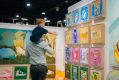 A small boy rides his dads shoulders at the Affordable Art Fair and points to a brightly coloured work that has caught his eye.