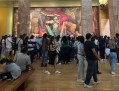 Large crowd in gallery looking at artworks. Damage