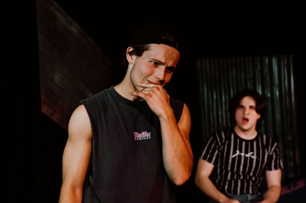 A young man looks shocked while another youth shouts at him in the background. A scene from Lunatix Theatre's 2025 production of 'Blackrock' at The MC Showroom.