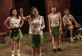 Four school girls dressed in uniform with white blouses and light green skirts.
