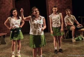Four school girls dressed in uniform with white blouses and light green skirts.