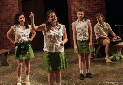 Four school girls dressed in uniform with white blouses and light green skirts.