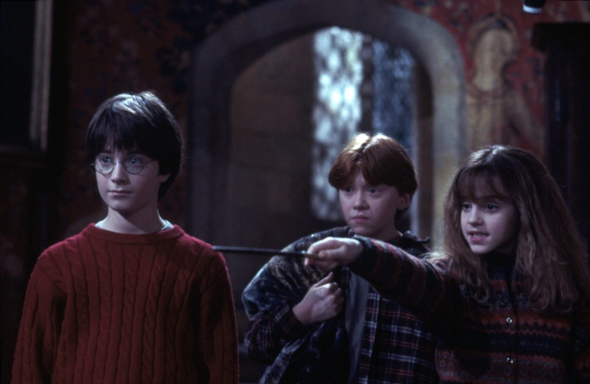 Two young boys and a young girl. The girl is pointing a wand.