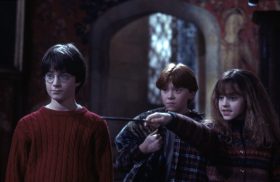 Two young boys and a young girl. The girl is pointing a wand.