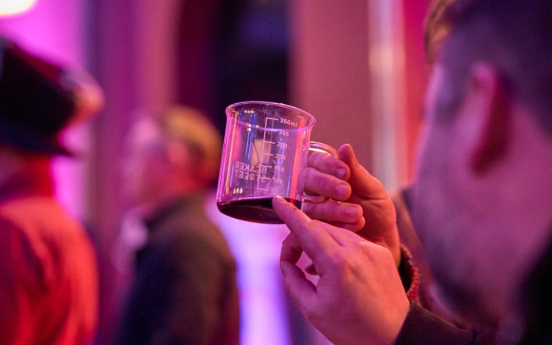 A figure cropped off from the right of the photo only showing their hand holding a beaker-like mug.