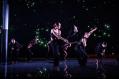 Dancers in black costume. The stage and lighting are also black.