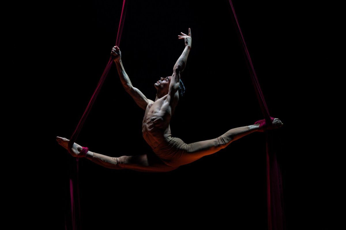 A male acrobat performs the splits, his body held aloft by aerial straps, in a scene from 'La Clique' at Adelaide Cabaret Festival.