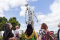 A large scale figure installation. Several people are looking up at it.