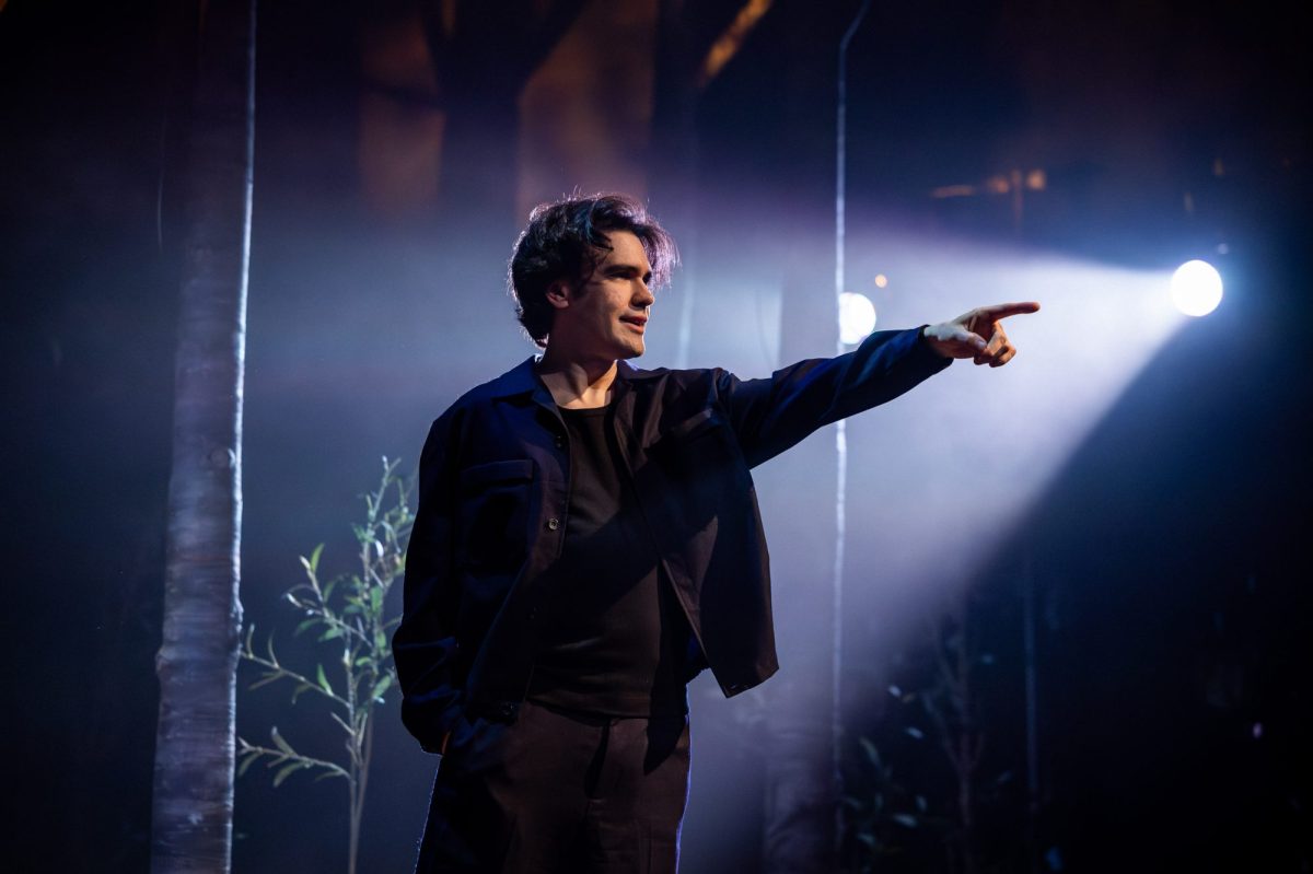 A man in black with his left arm outstretched.