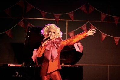 A drag queen with blonde wig and a red costume.