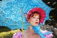 A woman in a bonnet with a light blue sun umbrella.