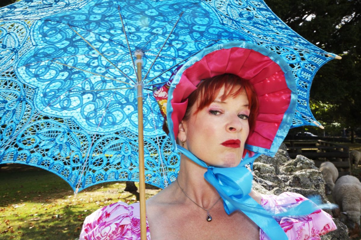 A woman in a bonnet with a light blue sun umbrella.