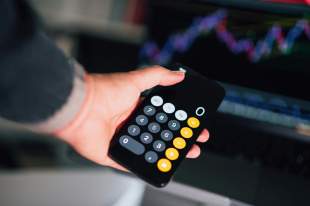 philanthropic giving: a photograph of a man's hand holding a calculator.
