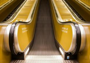 An escalator shot from the bottom with yellow sides. On the move.