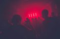 A dimly lit rave space, possibly a grief rave, shrouded in red light.