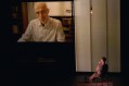 A bald man is on a large screen. Below him is a man looking up at him. ECHO, Every Cold-Hearted Oxygen