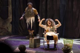 A woman sitting on a chair and a man standing behind her. They are both badly dressed in dirty rags an with wild, unkempt hair. The Twits. Roald Dahl.
