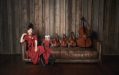 Photo of Hiromi wearing a red dress sitting on a leather couch alongside four string quartets.