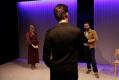 A man in a black suit has his back to us. He's facing a woman and a man who are standing apart.