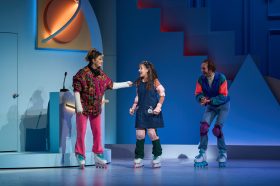 Two women and a man in colourful clothes on roller skates. Kimberly Akimbo
