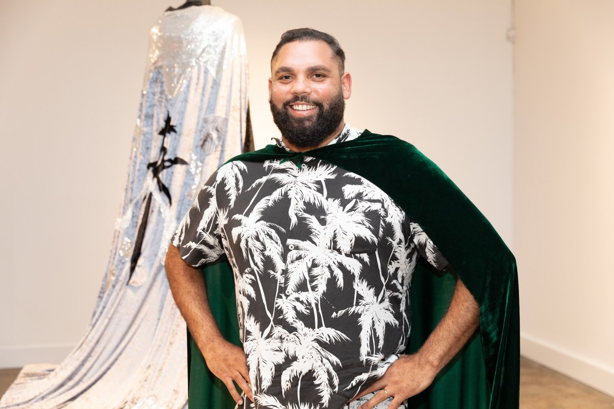Indigenous artist wearing palm tree tee shirt and green cape. Dennis Golding.