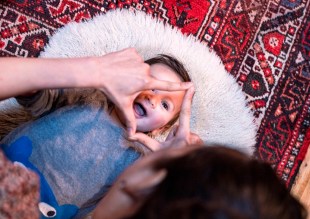 Carer playing creatively with a newborn at home. Glow