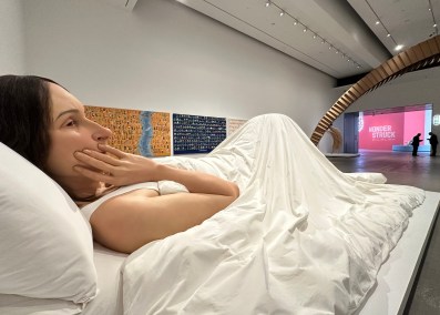 hyperreal sculpture of woman in bed in gallery setting. QAGOMA