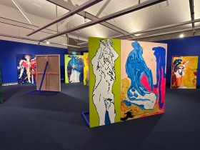 View of gallery installation with abstract colourful paintings, and blue gallery walls. Tom Polo