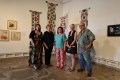 Five middle-aged Caucasian artists standing in a gallery with beige walls and artworks, including four long hanging tapestry or textile pieces. 2025 Miles Franklin Award, Siang Lu. Arts prize winners, recipients, shortlists.