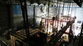 Theatre workers: a photograph of a theatre stage including the rafters, rigging and scaffolding structures above and behind the theatre stage.